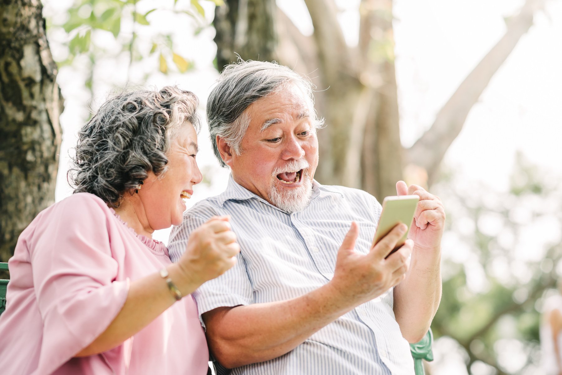 Happy Senior Couple Using Smartphone with Excitement 